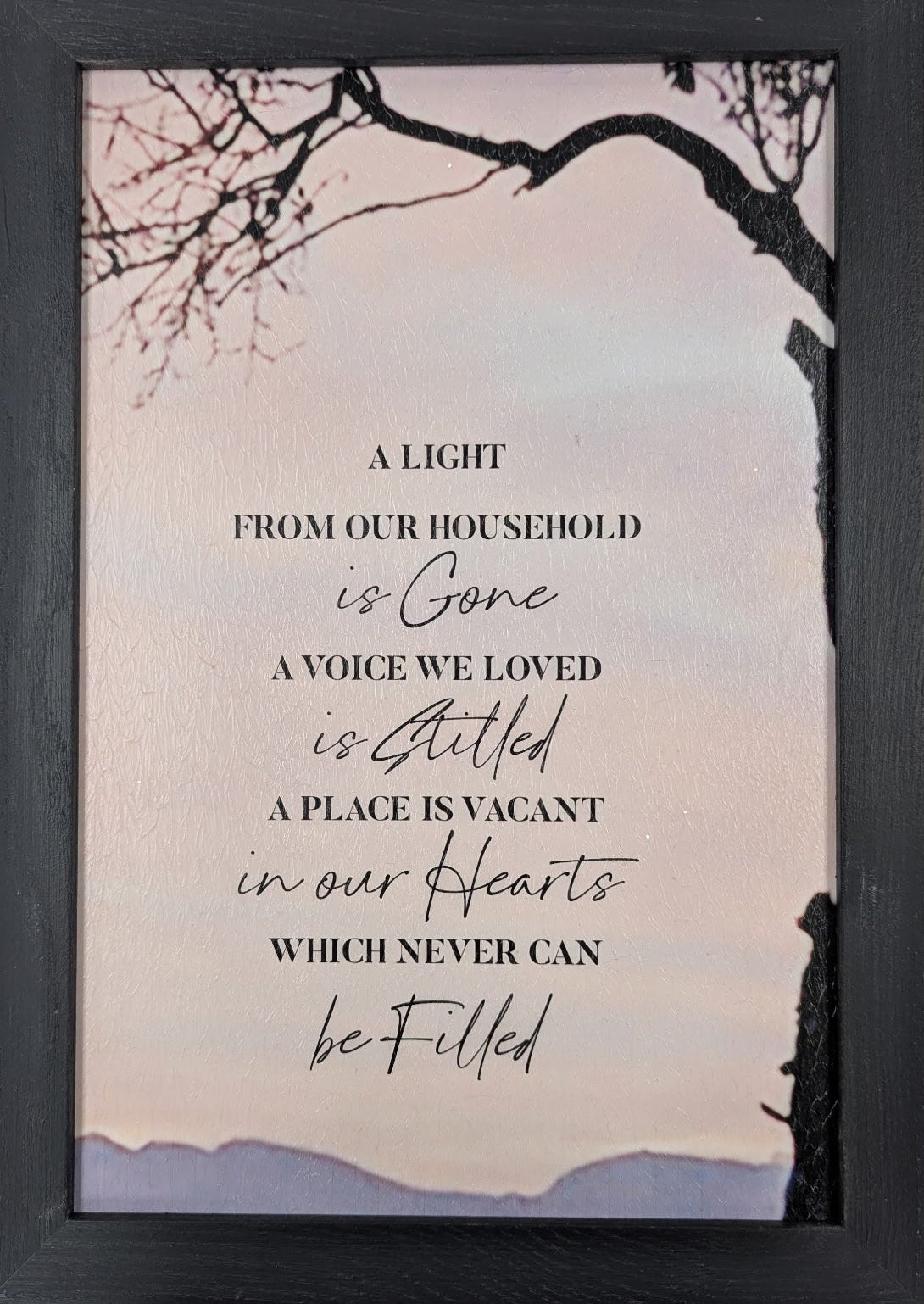 Framed print with a quote on a light pink background with tree branches.