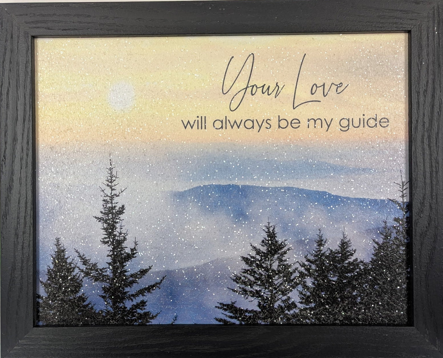 Framed artwork with a mountain and tree scene and text 'Your Love will always be my guide' on a light background.