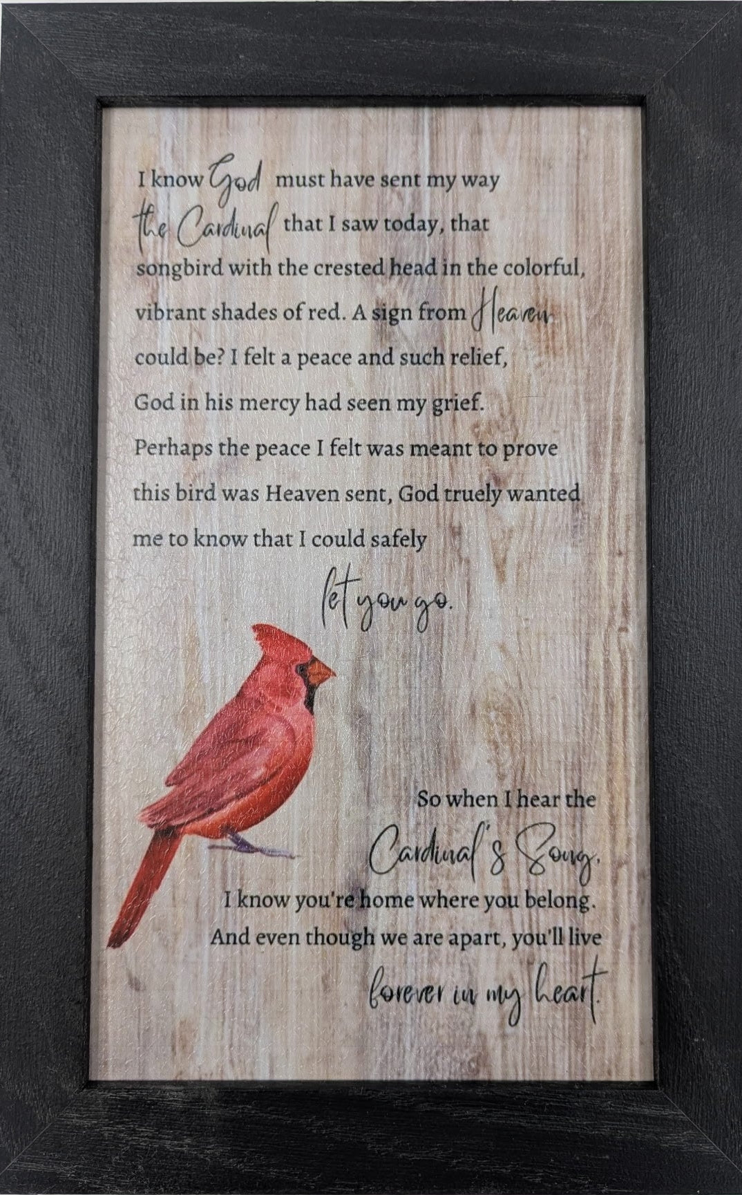 Framed print with a red cardinal illustration and text on a wooden background