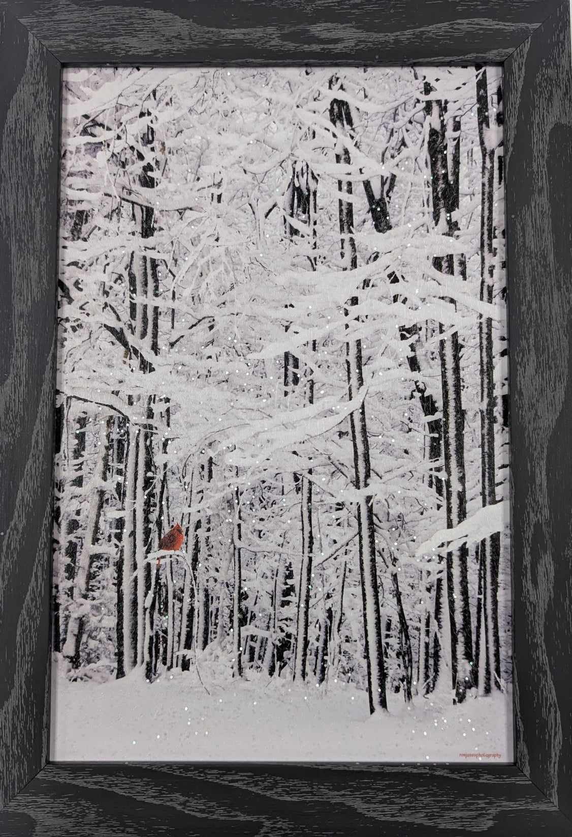 Framed artwork of a snowy forest scene with a black frame.