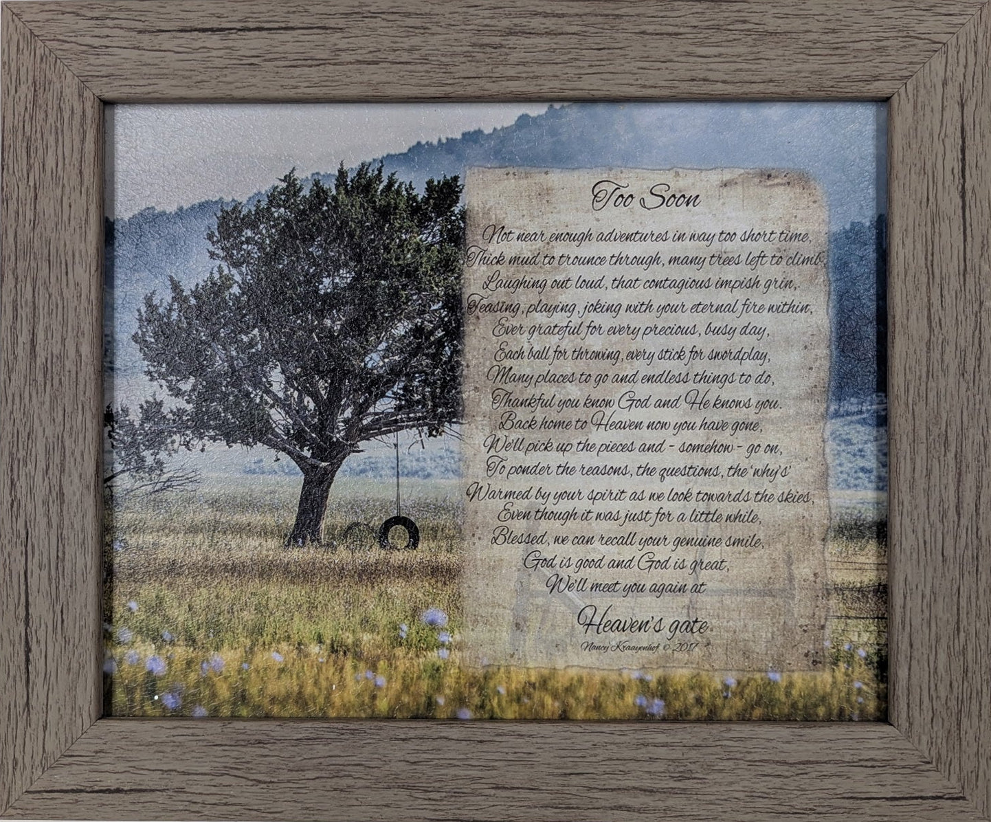 Framed artwork with a tree and field scene on a white wall