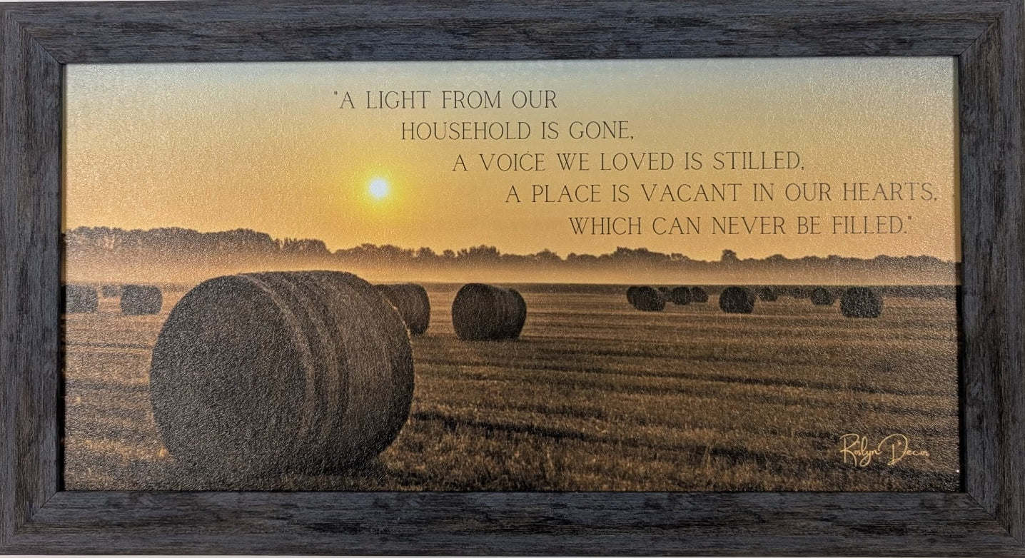 Framed artwork with a sunset over a field and text on a white wall.