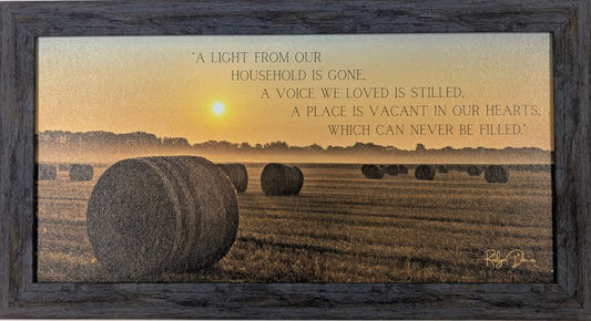 Framed artwork with a sunset over a field and text on a white wall.