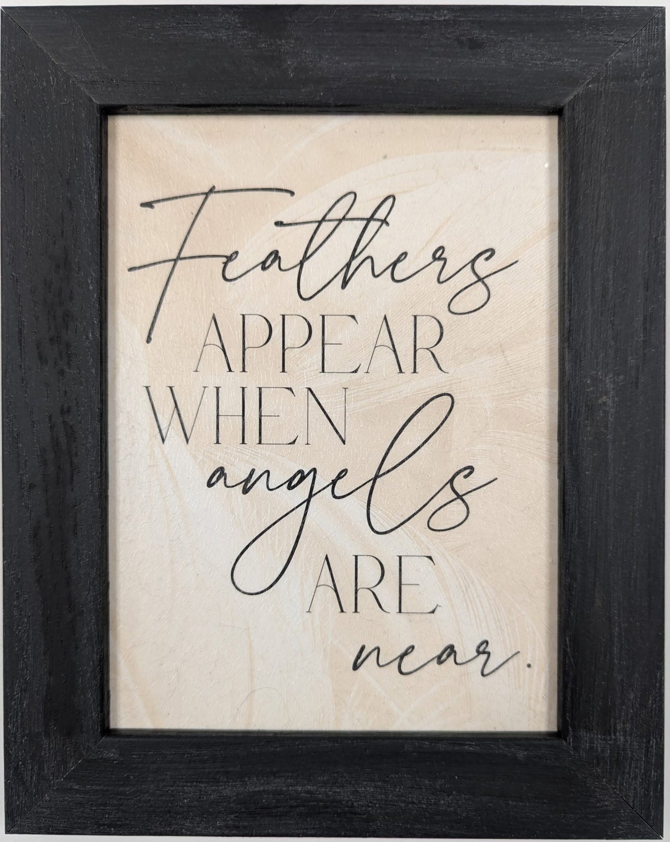 Framed print with motivational quote 'Feathers appear when angels are near' on a light background