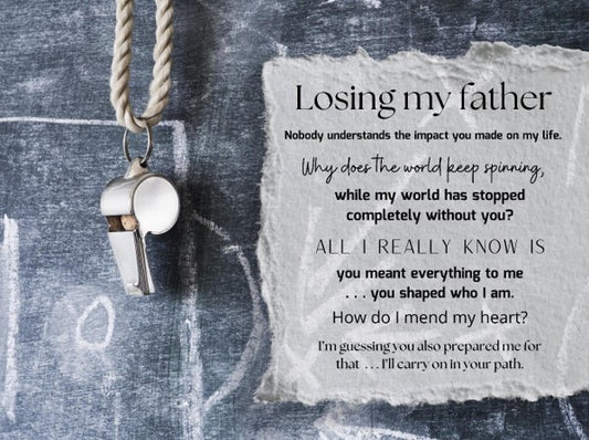 Whistle hanging on a textured surface with a piece of paper displaying a heartfelt message about losing a father.